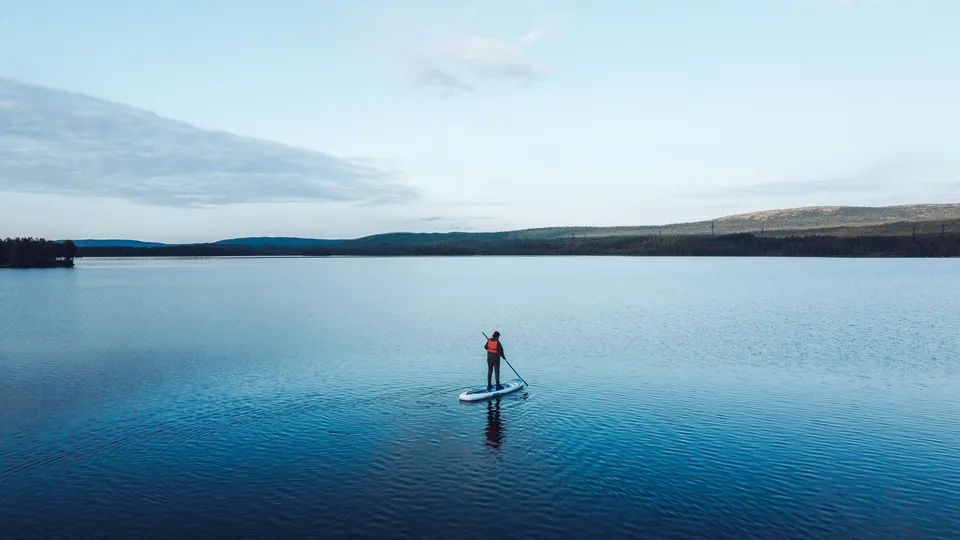Ensam SUP-paddlare på en stilla sjö