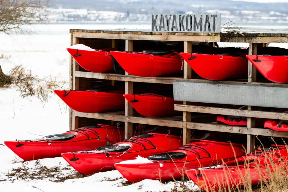 Röda kajaker i vinterförvaring vid sjön